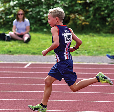 a young child running a sprint on a track