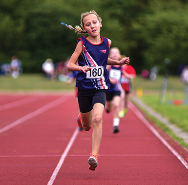 a girl in SSAthletics' vest running on a track with others behind her
