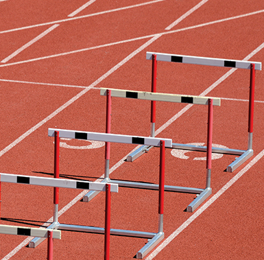 five hurdles on a red tarmac track