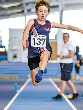 a child in SSAthletics' garb performing a long jump