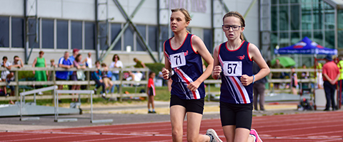 two teenagers running on a track at an athletics meet