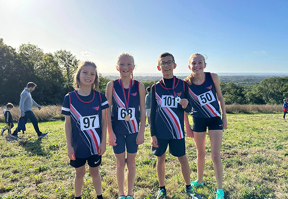 four children in SSAthletics garbs, posing for a photo in a field after a track event