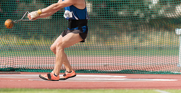 a person performing a hammer throw with a orange hammer